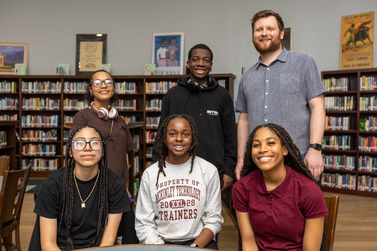 Group photo of students and a teacher in the library